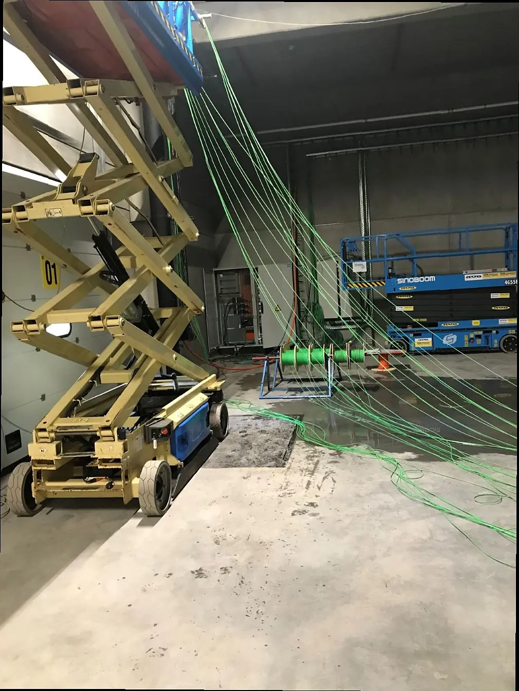 Warehouse hall with cable routes installed from scissor lifts
